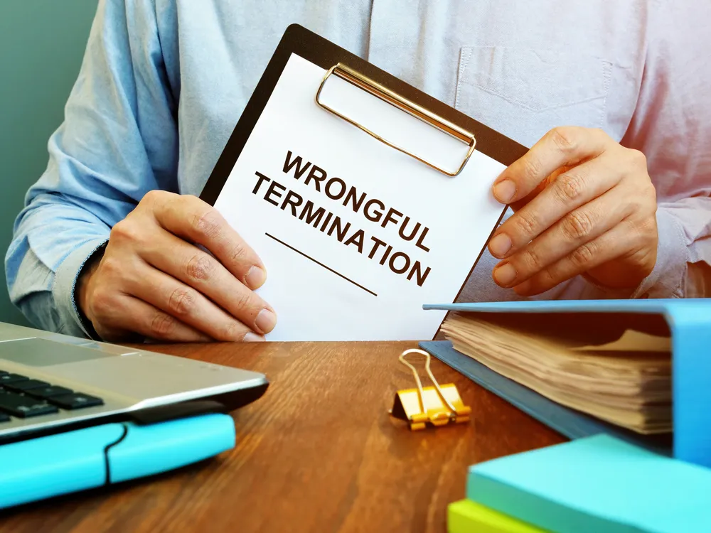 A man holding a clipboard with a paper that has wrongful termination written on it.