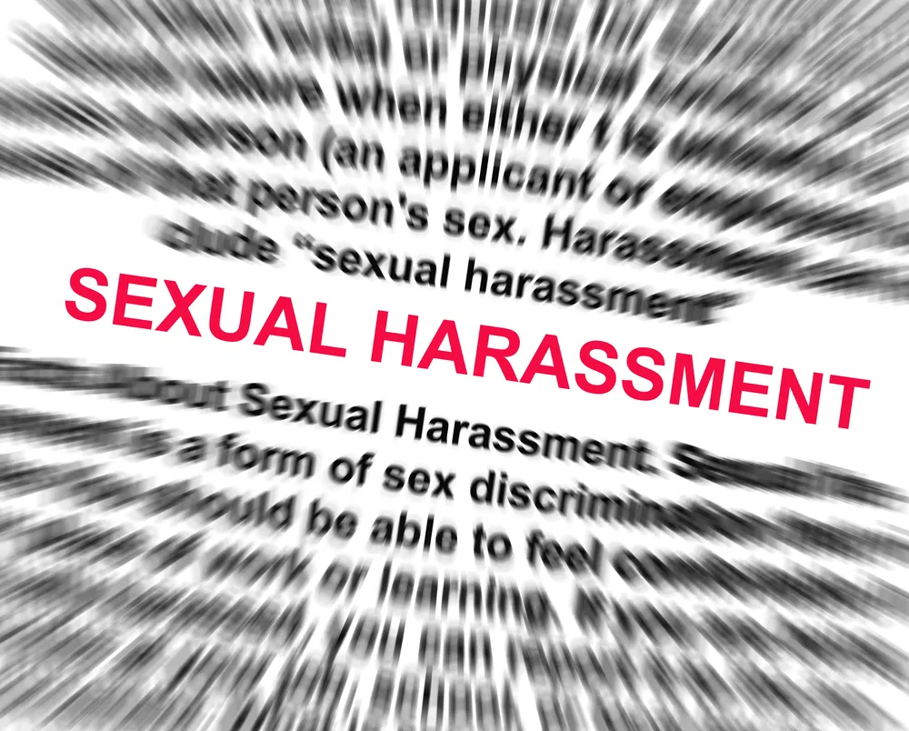 Sexual Harassment writing in red with blurred writing behind it.