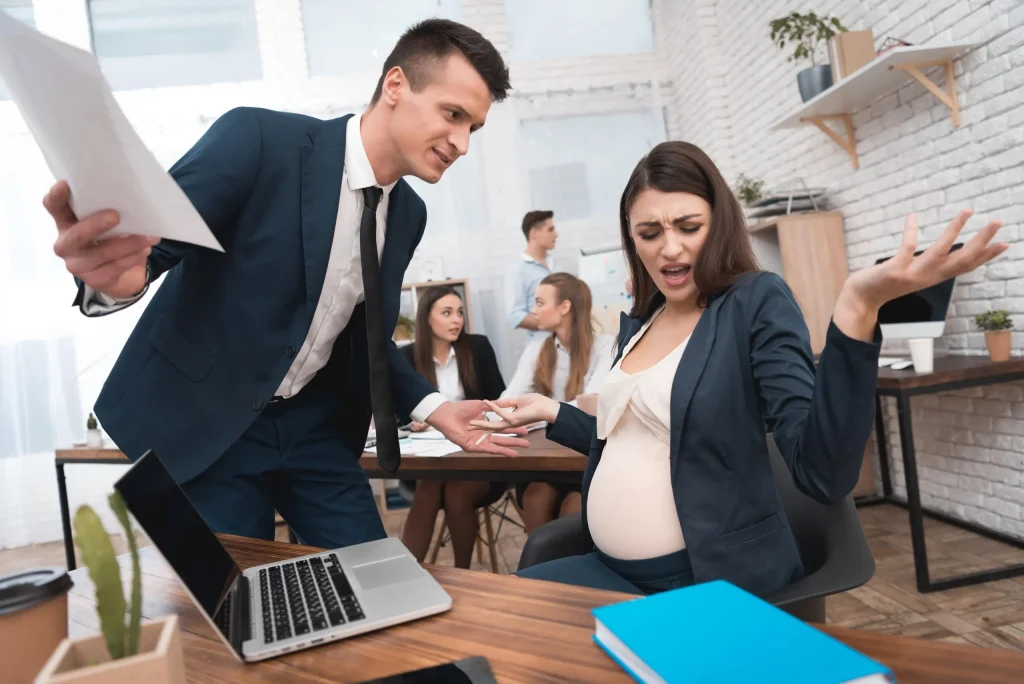 A pregnant woman being chewed out by her employer while sitting at her desk. Our discrimination lawyers in Kansas City have what it takes to fight against workplace discrimination.