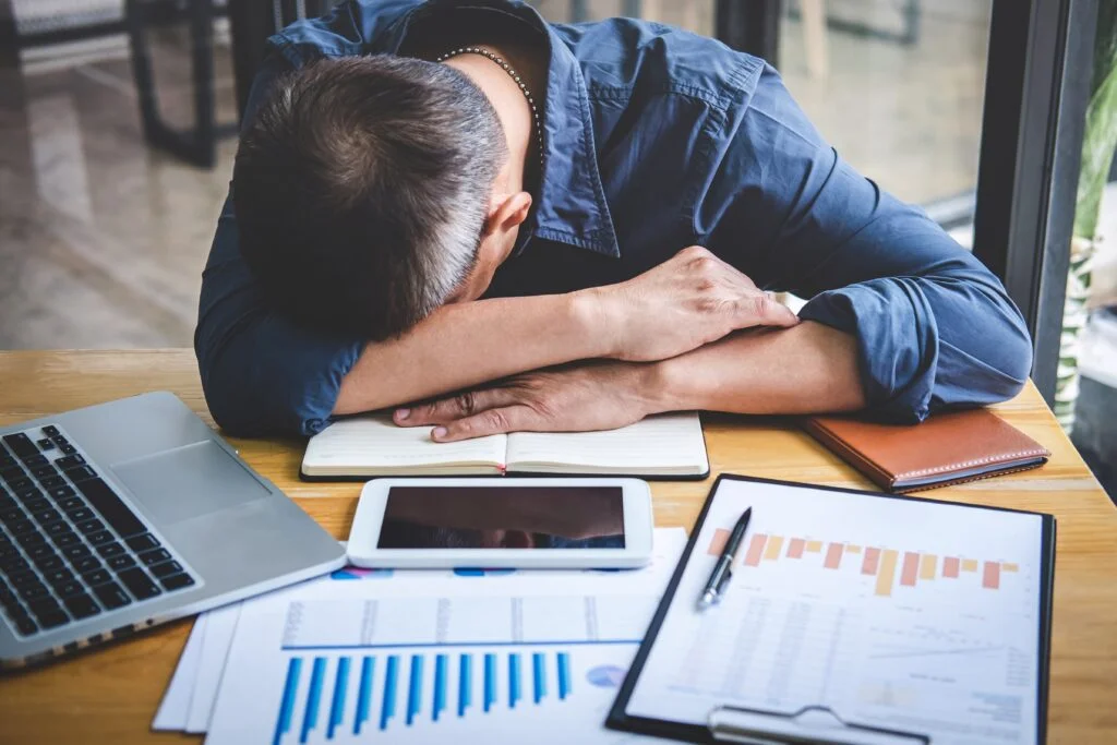 A man with his head down at his work desk because he is exhausted by being overworked with little meal or break opportunities. Our employment attorney in Kansas City is experienced at helping to fight injustices in the workplace.