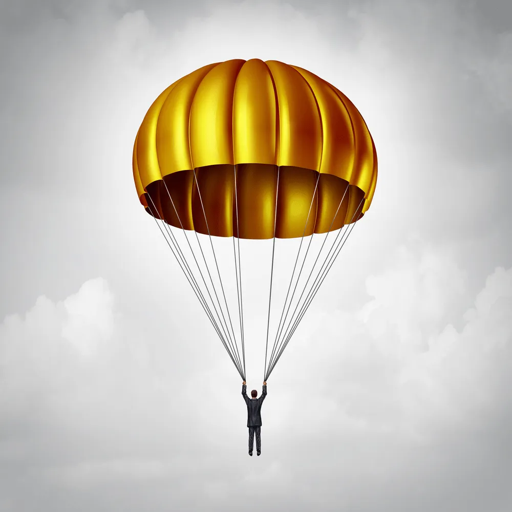 A man in a suit hanging onto and floating from a gold parachute.