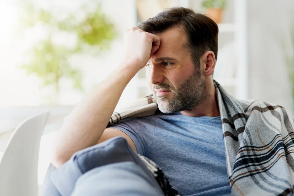 A man sitting on his couch contemplating his options after recovering from near life threatening blood clots as a result of a defective port catheter device.