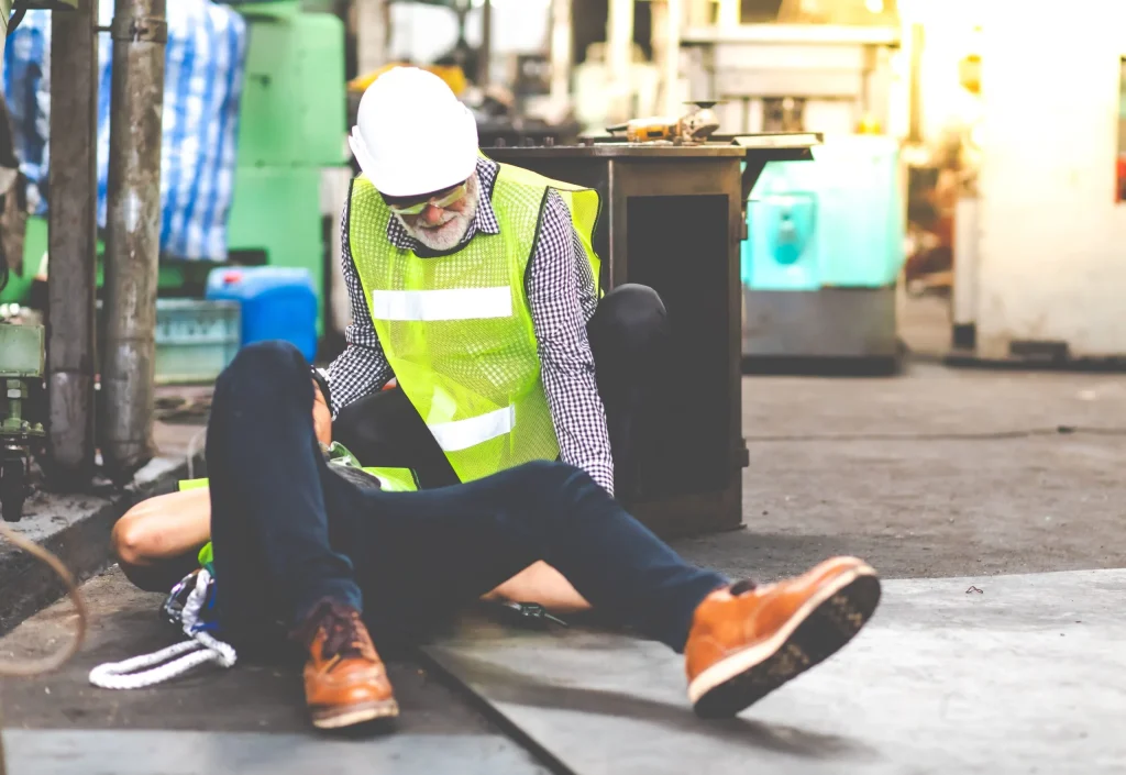 A worker being helped by a coworker after slipping and injuring himself at work. A Missouri personal injury attorney can help defend your case.