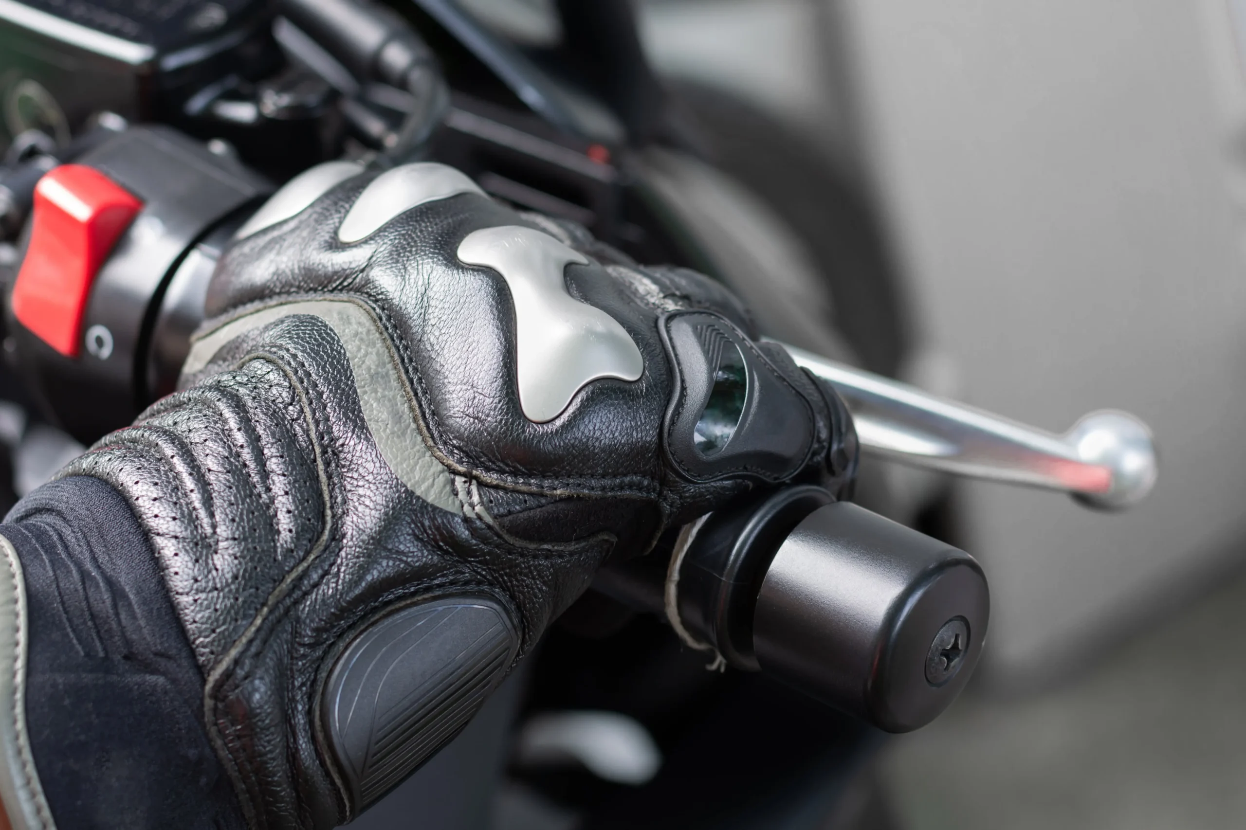 A motorcyclist's hand on the handlebar of his bike.