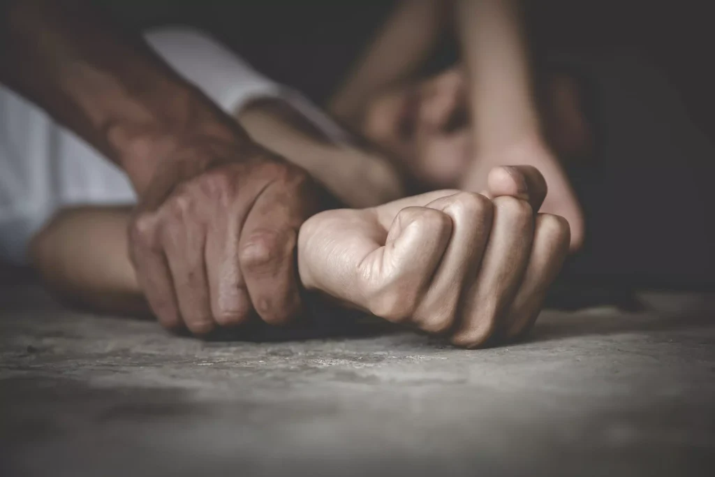 A man holding a woman's wrist on the ground.