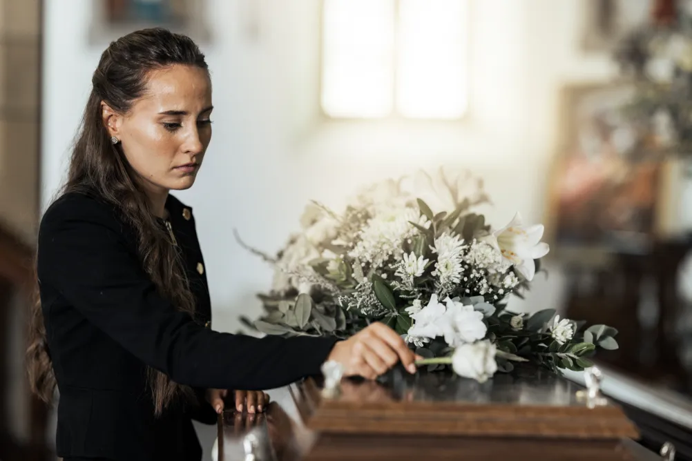 A woman putting flowers on a casket.