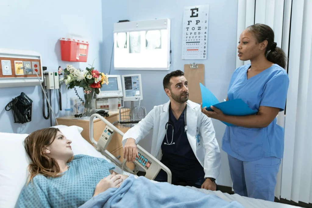 A woman in the hospital talking to her doctor and nurse.